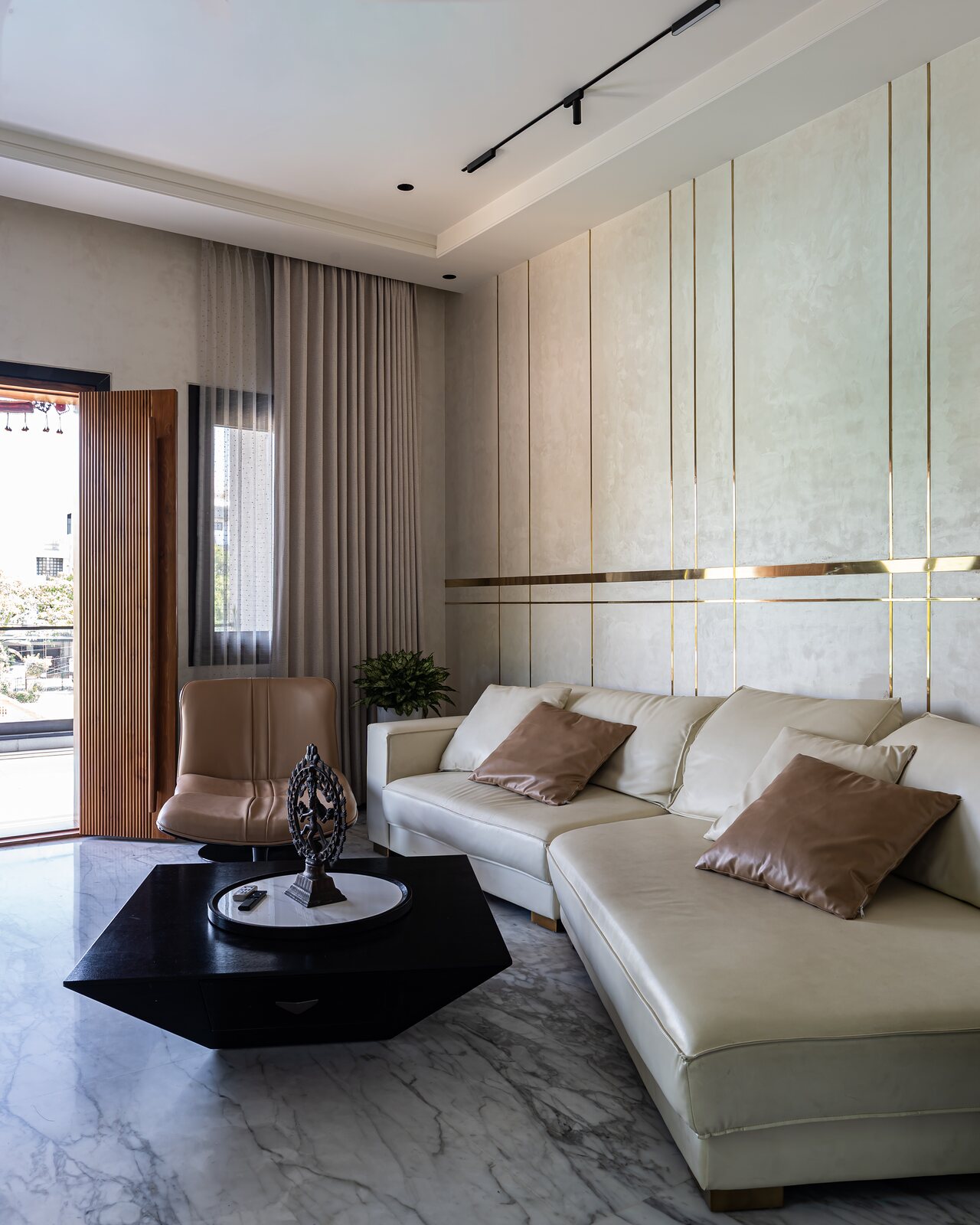 A second lounge, a beige sectional below gold wall lines.