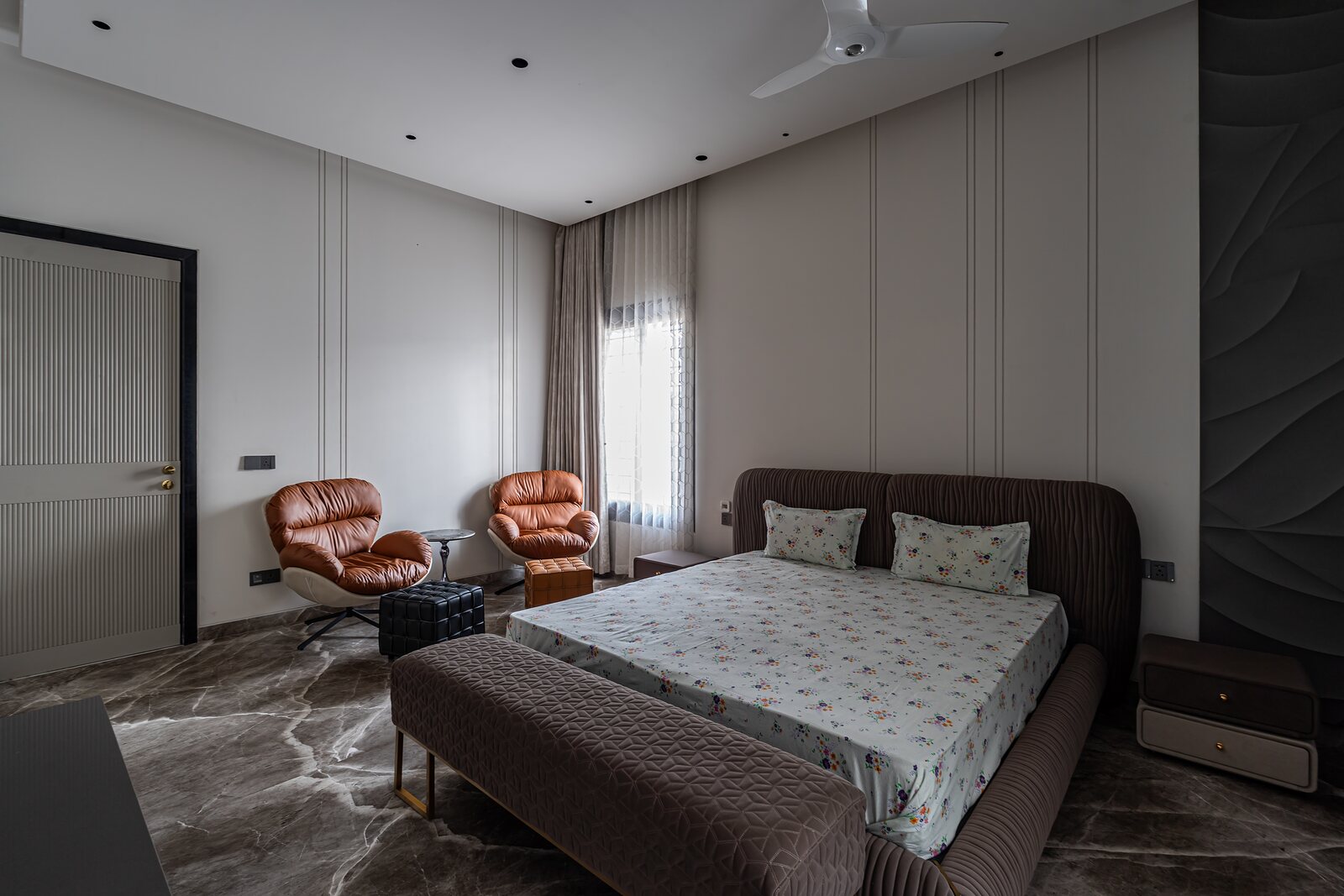 The master bedroom, leather lounge chairs beside the bed.