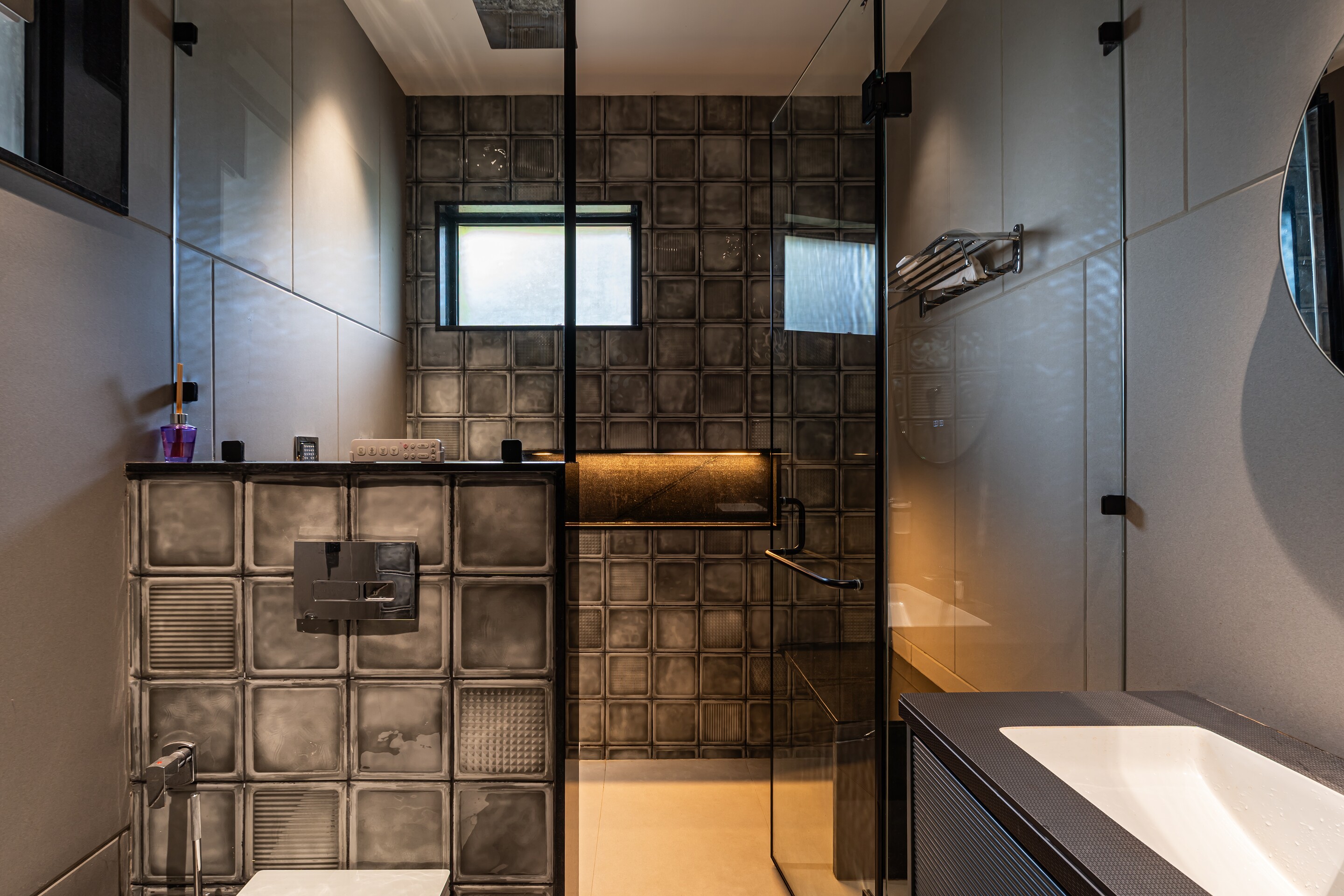 A bathroom in textured tile with a round mirror.