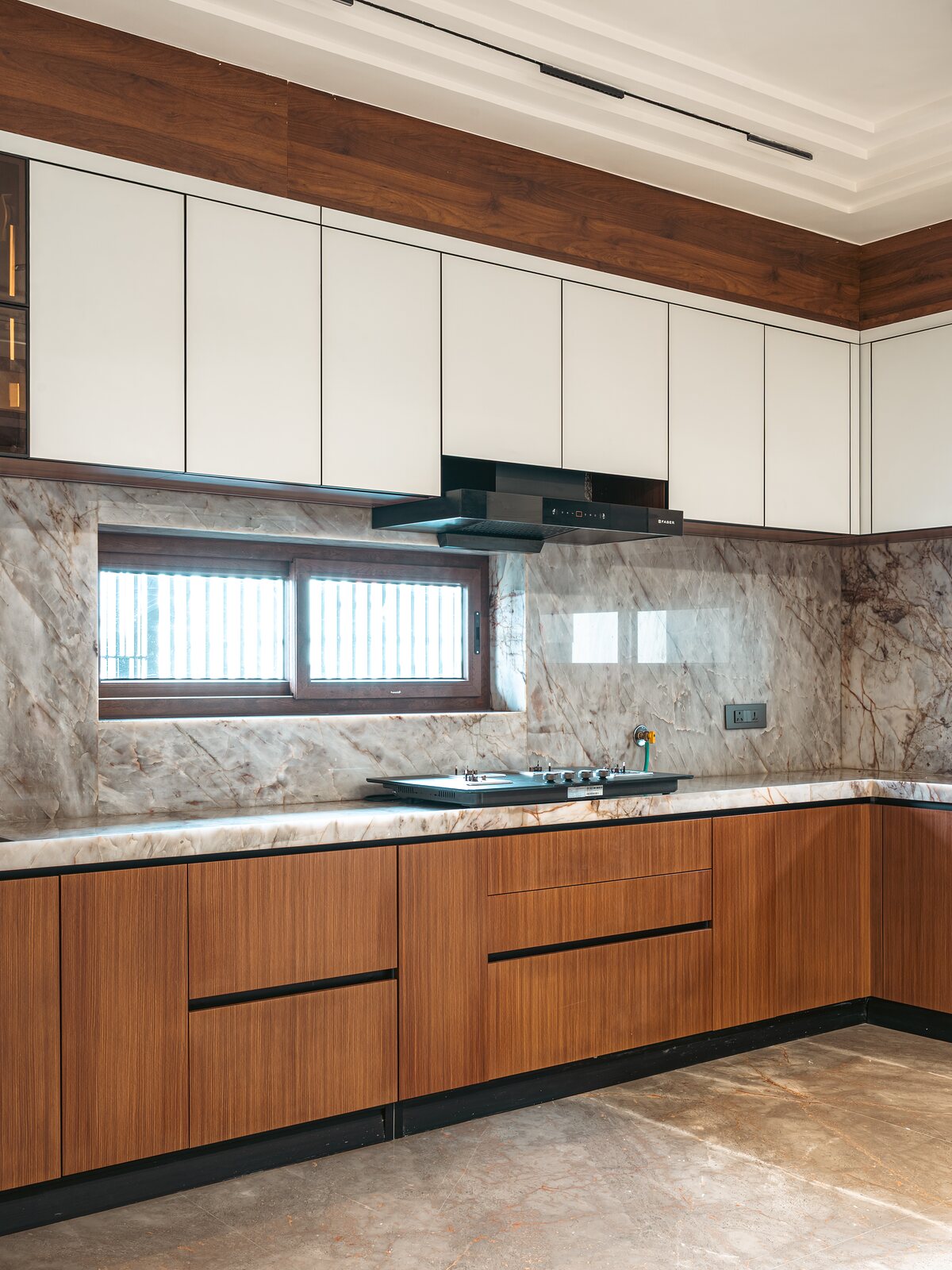The cooktop runs along the marble backsplash.