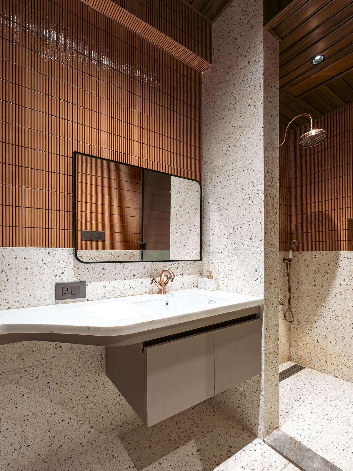 A terrazzo vanity under a black mirror.