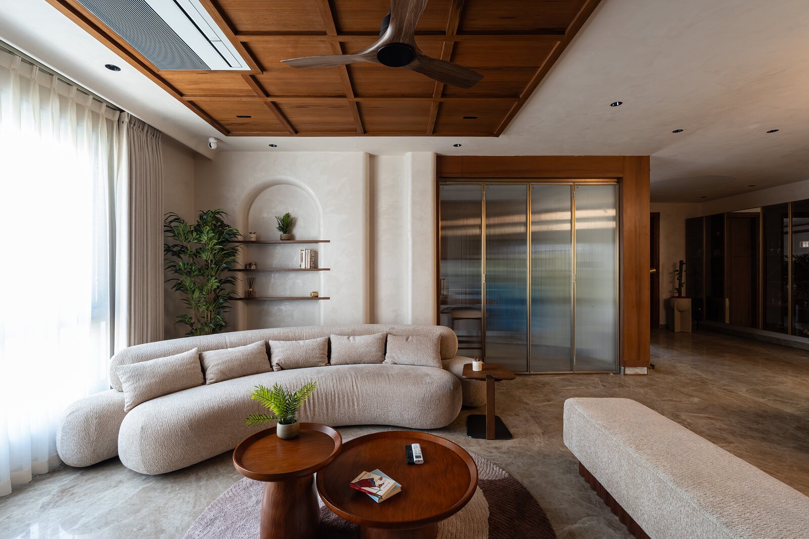 A curved sofa under a coffered walnut ceiling, Tsuki House.