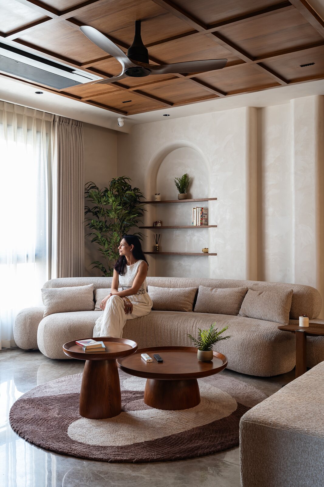 The sofa curves around a walnut table.