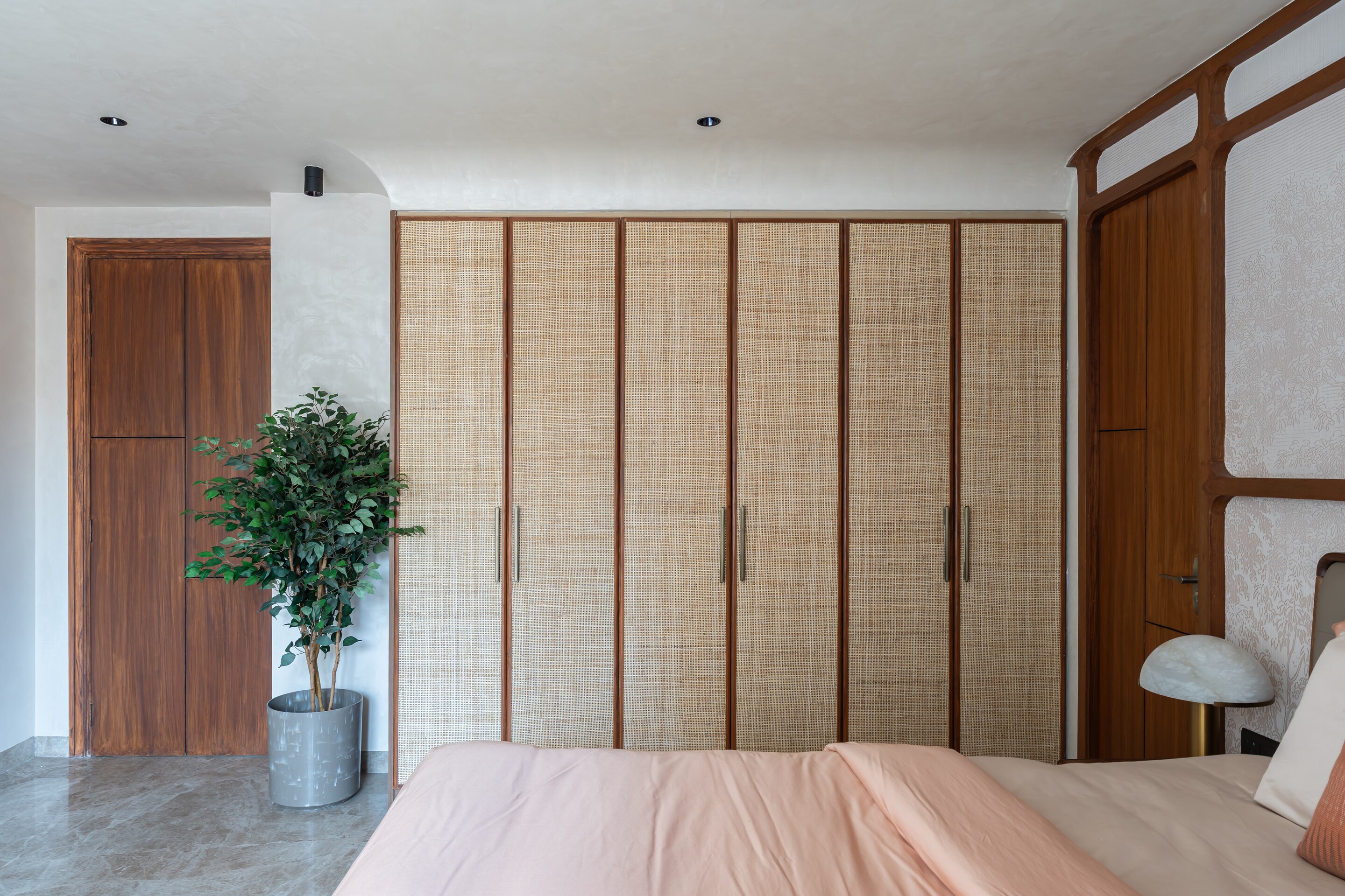 Cane wardrobes beside a walnut door.