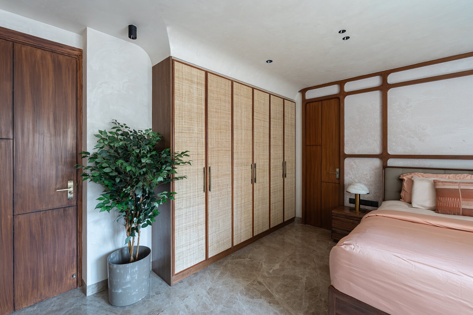 A wall of cane and walnut wardrobes.