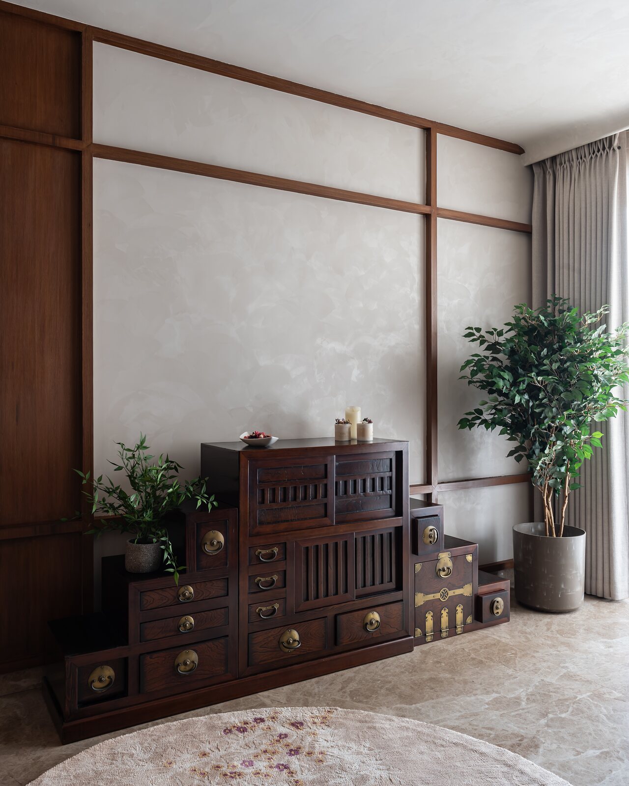 A stepped tansu chest against the grid wall.