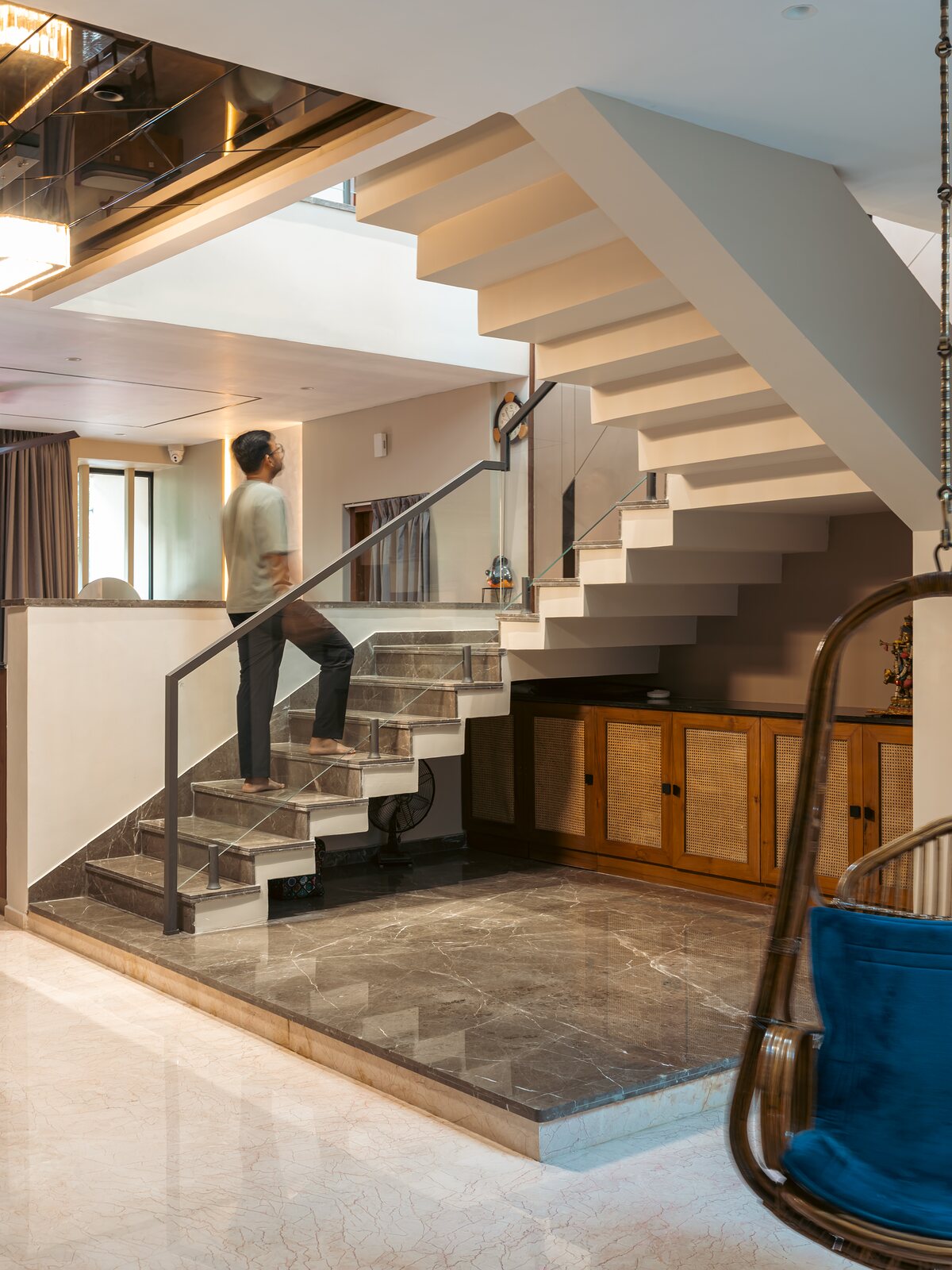 The double-height hall, a cane swing by the window.
