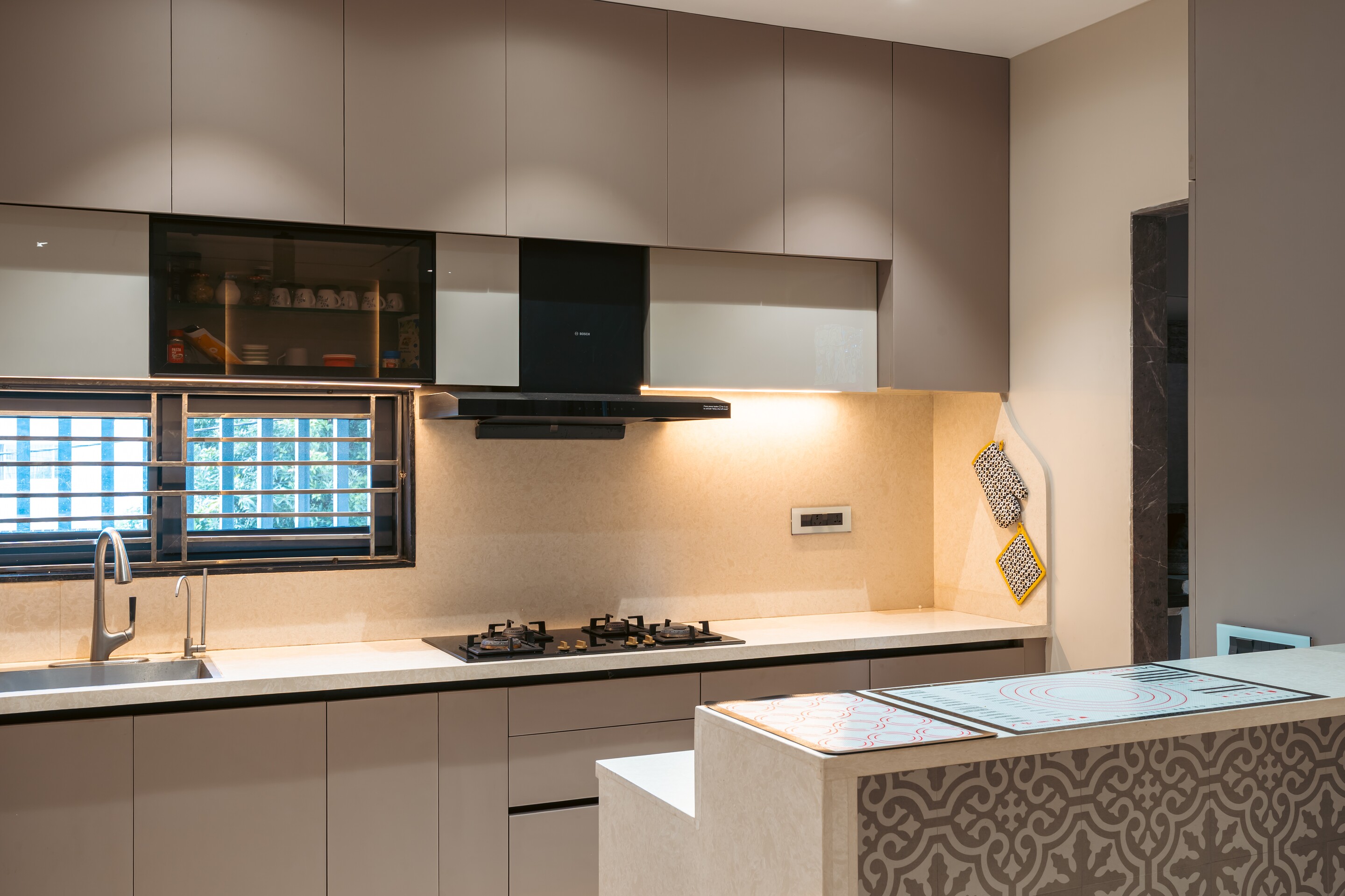 The kitchen. A patterned island under a black hood.
