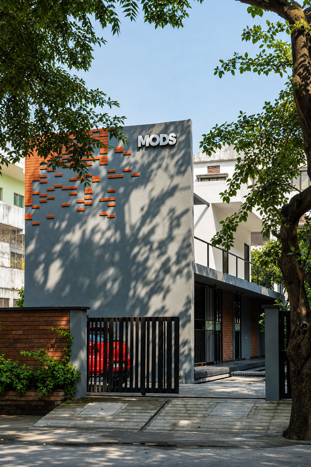 The street facade. Perforated brick and the MODS mark.