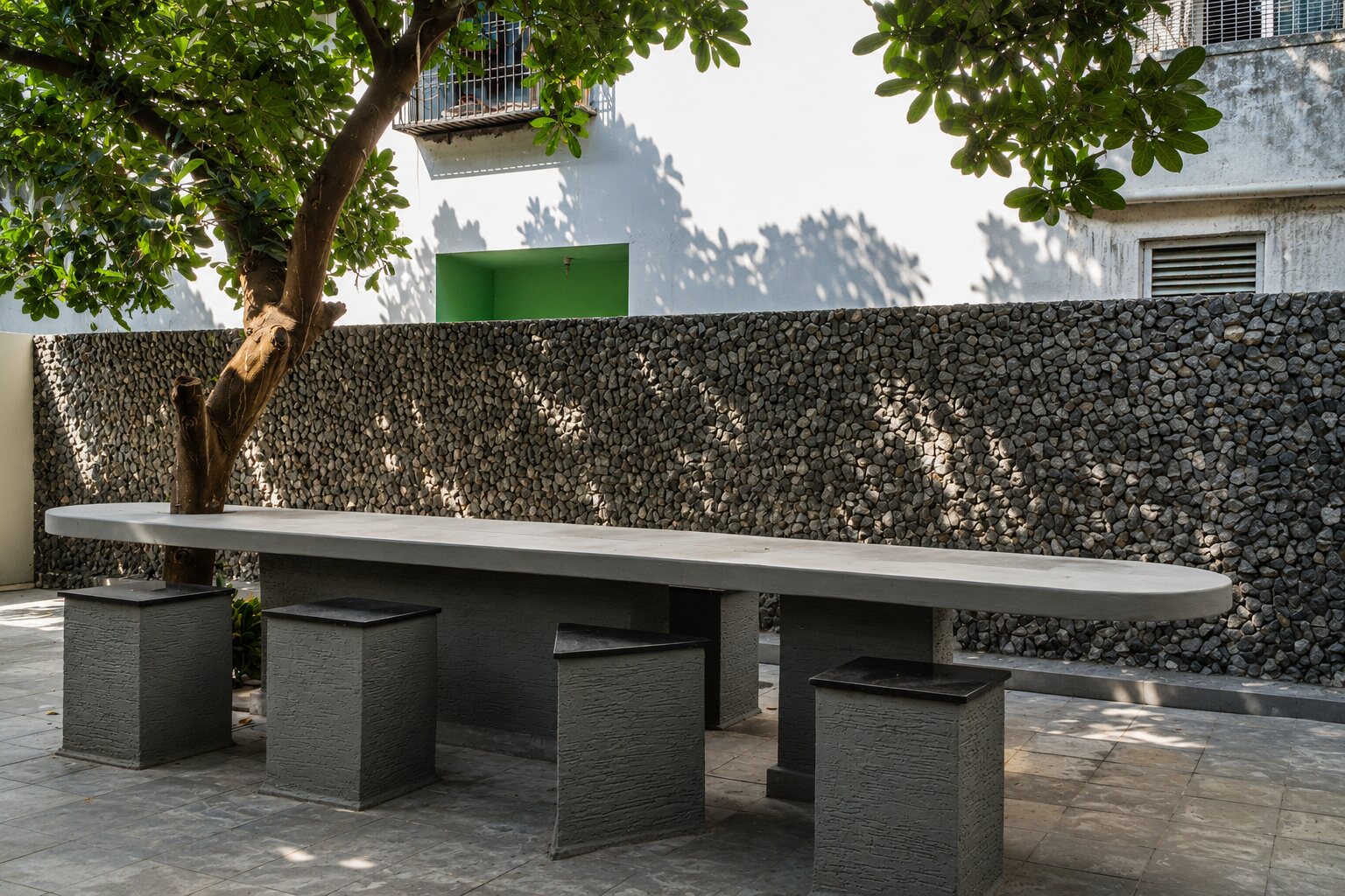 The concrete bench under the mango tree.
