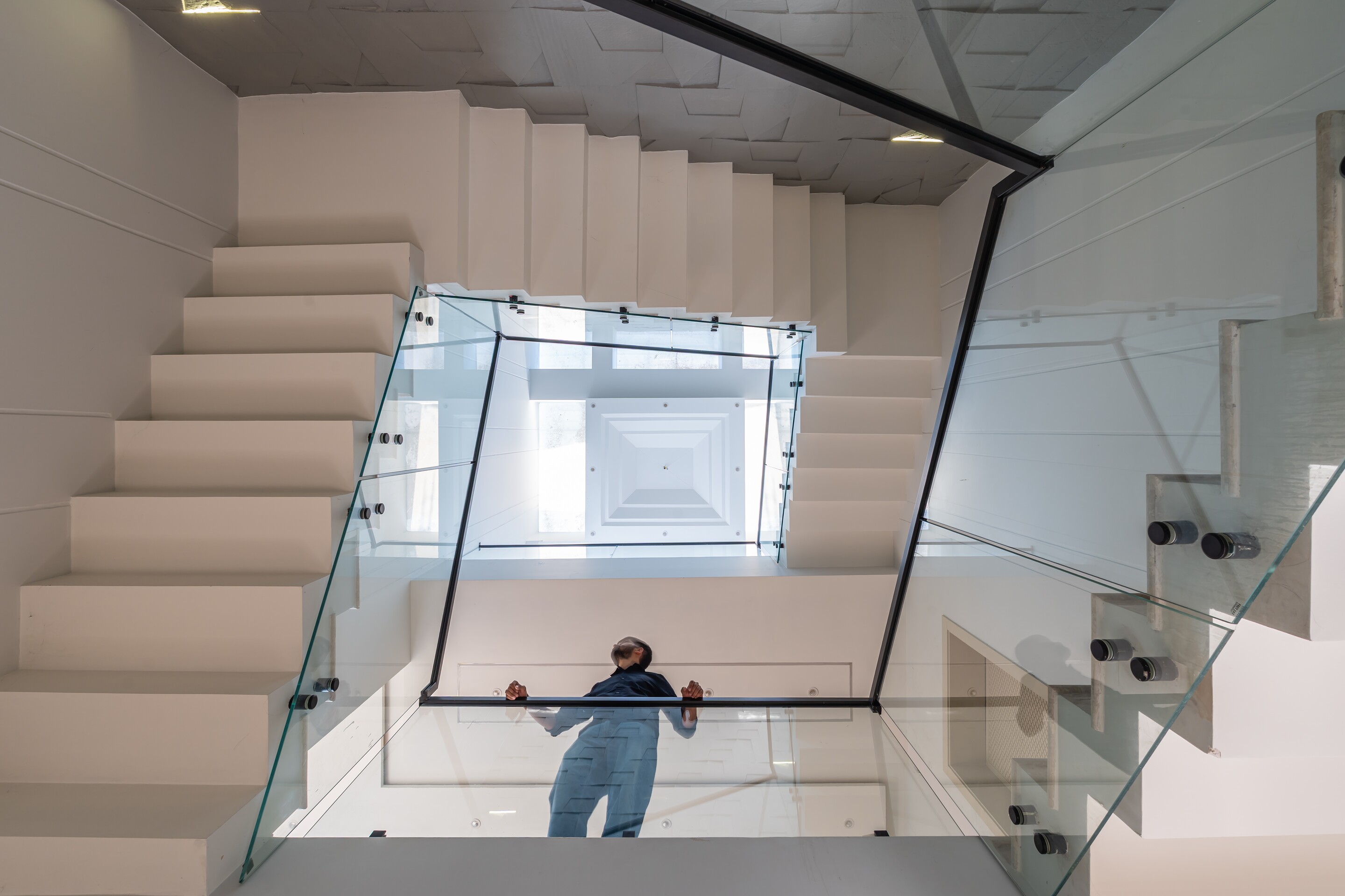 The stair void, glass rails dropping through the section.