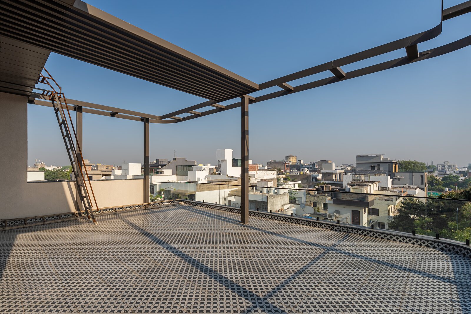 A steel pergola frames the roof terrace and the skyline.
