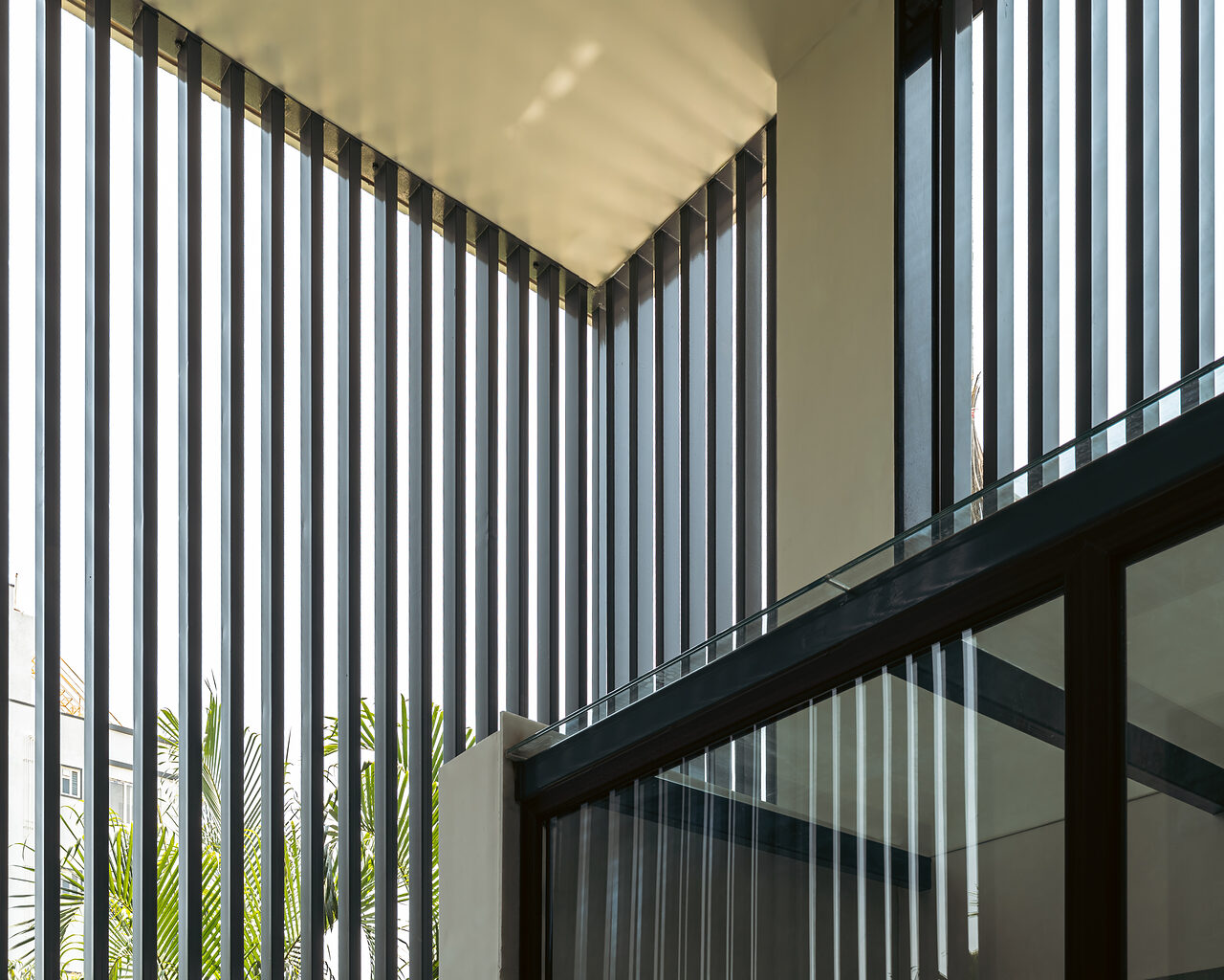 Vertical fins stripe the light across the court wall.