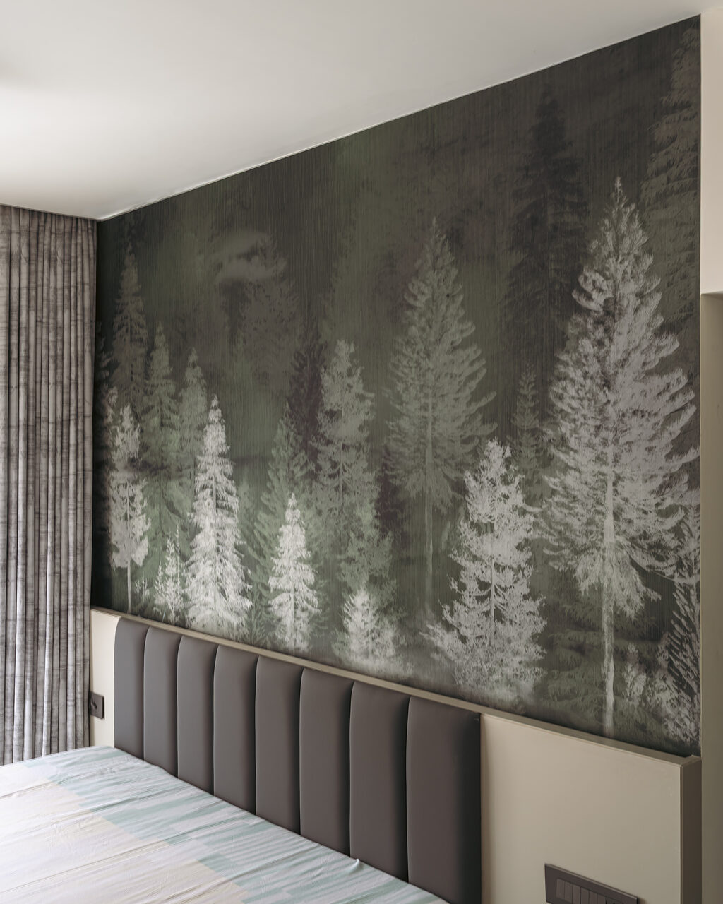 A printed pine mural behind the upholstered headboard.