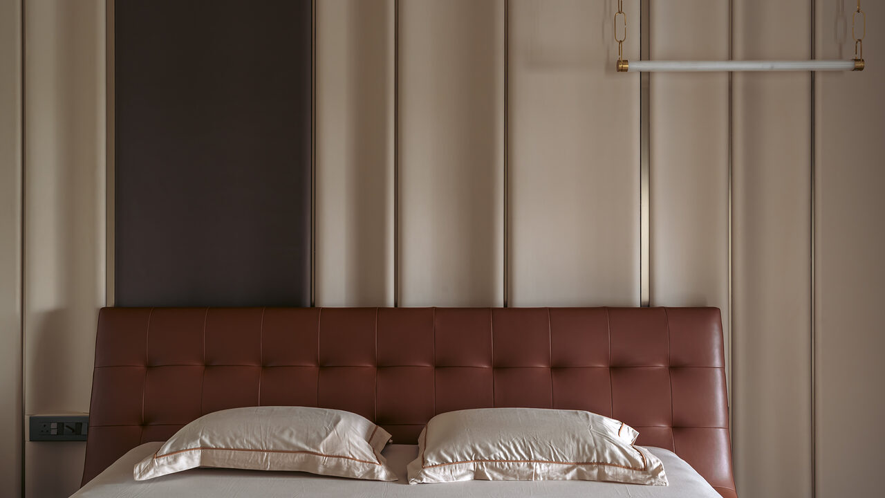 A tufted oxblood headboard against panelled walls.