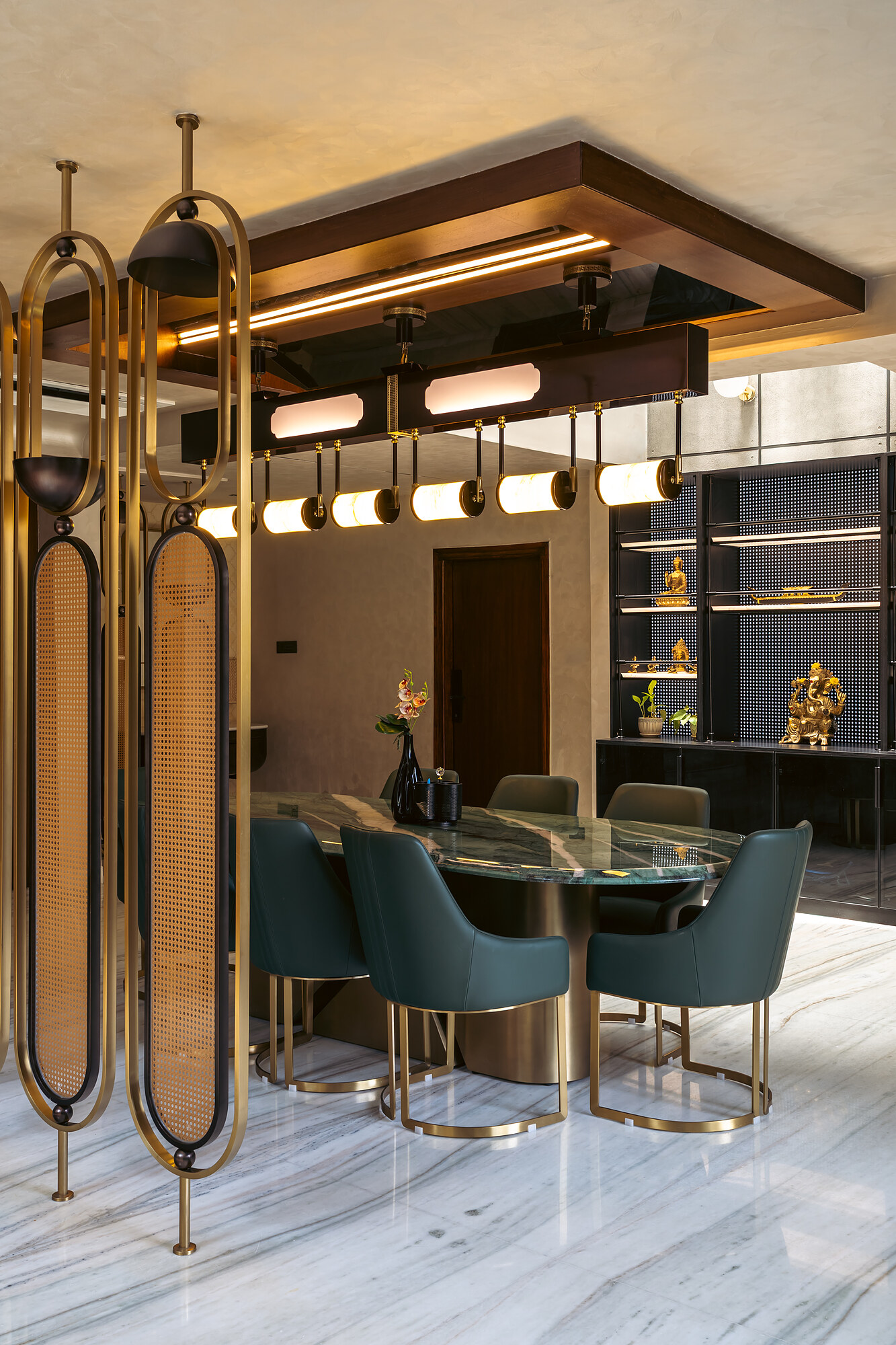 Green velvet chairs under a rail of brass pendants.