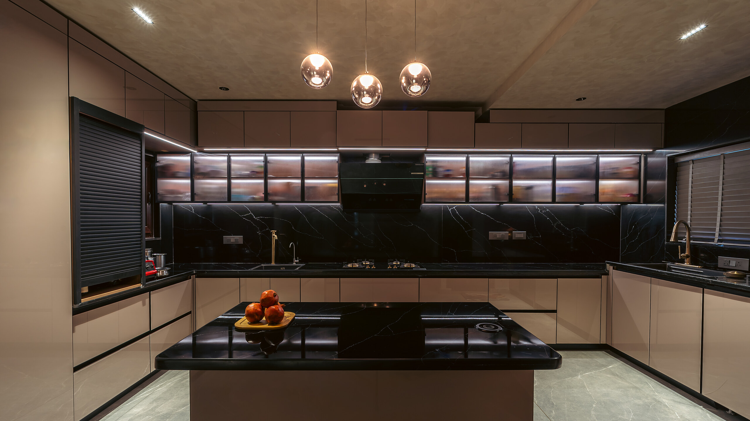 Black stone counters under lit glass cabinets.